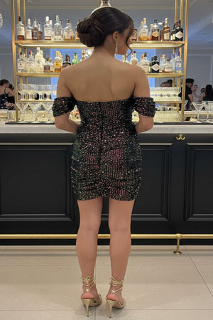 Woman in a floral dress standing in front of a bar with shelves of bottles.