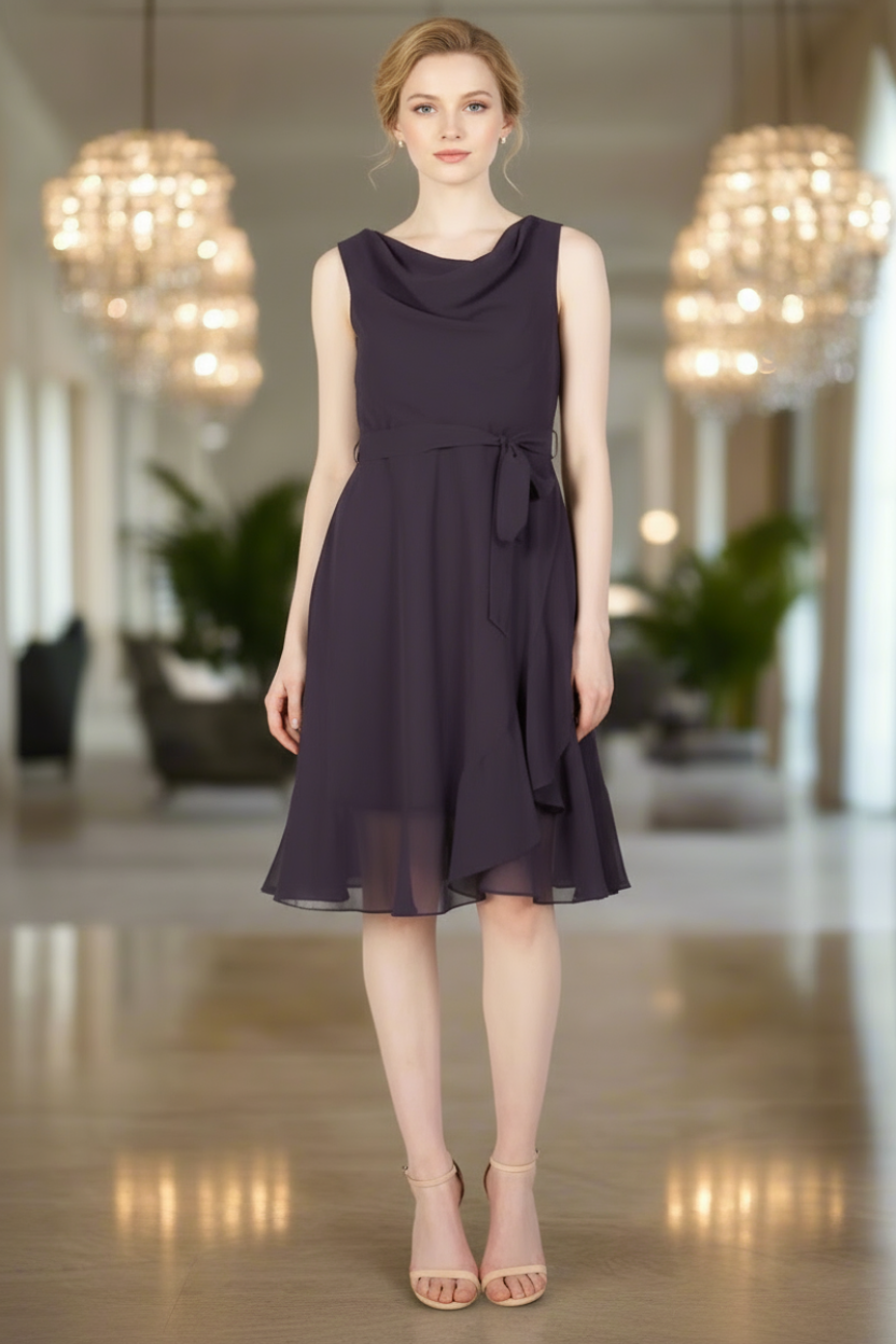 Woman wearing a dark purple dress in an elegant indoor setting with chandeliers.