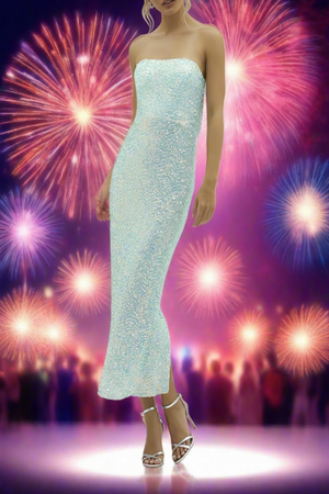 A model wearing a strapless, sequin cocktail dress in turquoise, with a cowl back and spaghetti straps, standing in a vibrant setting with fireworks in the background.