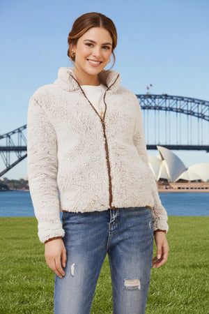 Woman wearing a cream sherpa jacket with a bridge and Opera House in the background