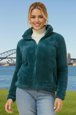 Woman wearing a teal fleece jacket with a bridge and water in the background