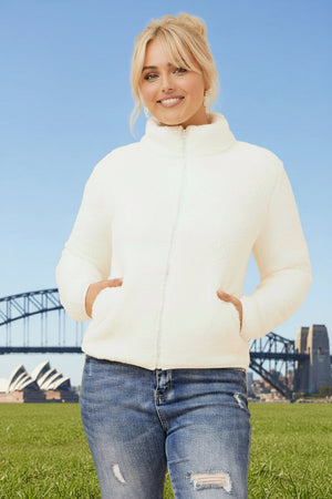 Woman wearing a white puffer jacket with a bridge and skyline in the background