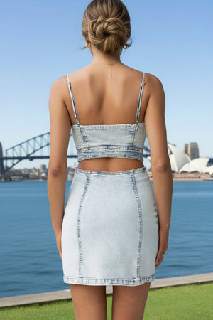 Woman wearing a denim outfit with a scenic background featuring a bridge and body of water.