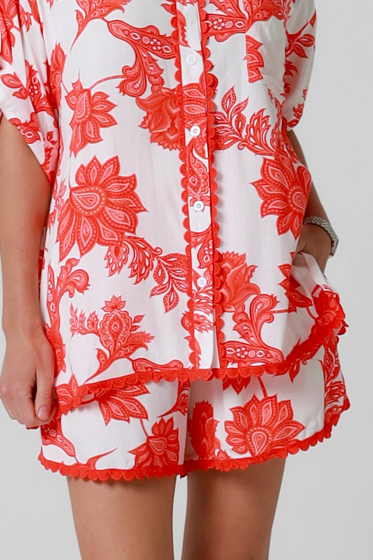 Woman wearing a red and white floral dress against a plain background