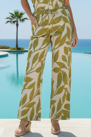 Person wearing a green and white leaf-patterned outfit standing against a stone wall.