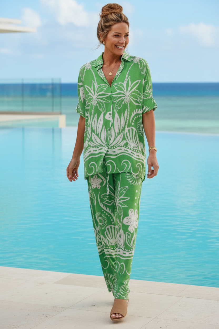 Person wearing a green and white patterned outfit with a pool and palm trees in the background