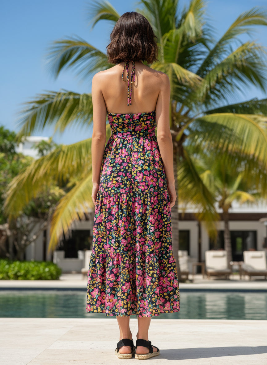 Woman in a floral dress standing by a pool with palm trees in the background