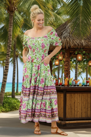 Woman in a floral dress standing by a tropical bar with palm trees in the background